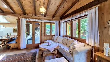 Ein Holzblockbau-Innenraum mit einer Couch, einem Tisch und großen Fenstern.