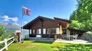 Eine Holzhütte mit Terrasse, Sitzgelegenheiten im Freien und einer Flagge.