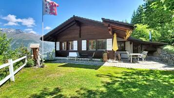 Eine Holzhütte mit Terrasse, Sitzgelegenheiten im Freien und einer Flagge.