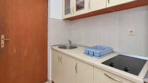 Une petite cuisine équipée d’un évier, d’un récipient en plastique bleu et d’une cuisinière.