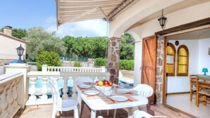 Eine Terrasse im Freien mit Esstisch und weißen Stühlen, umgeben von einem Steinsäule.