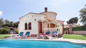 Ein Haus mit Swimmingpool, einer überdachten Terrasse und einem Garten.