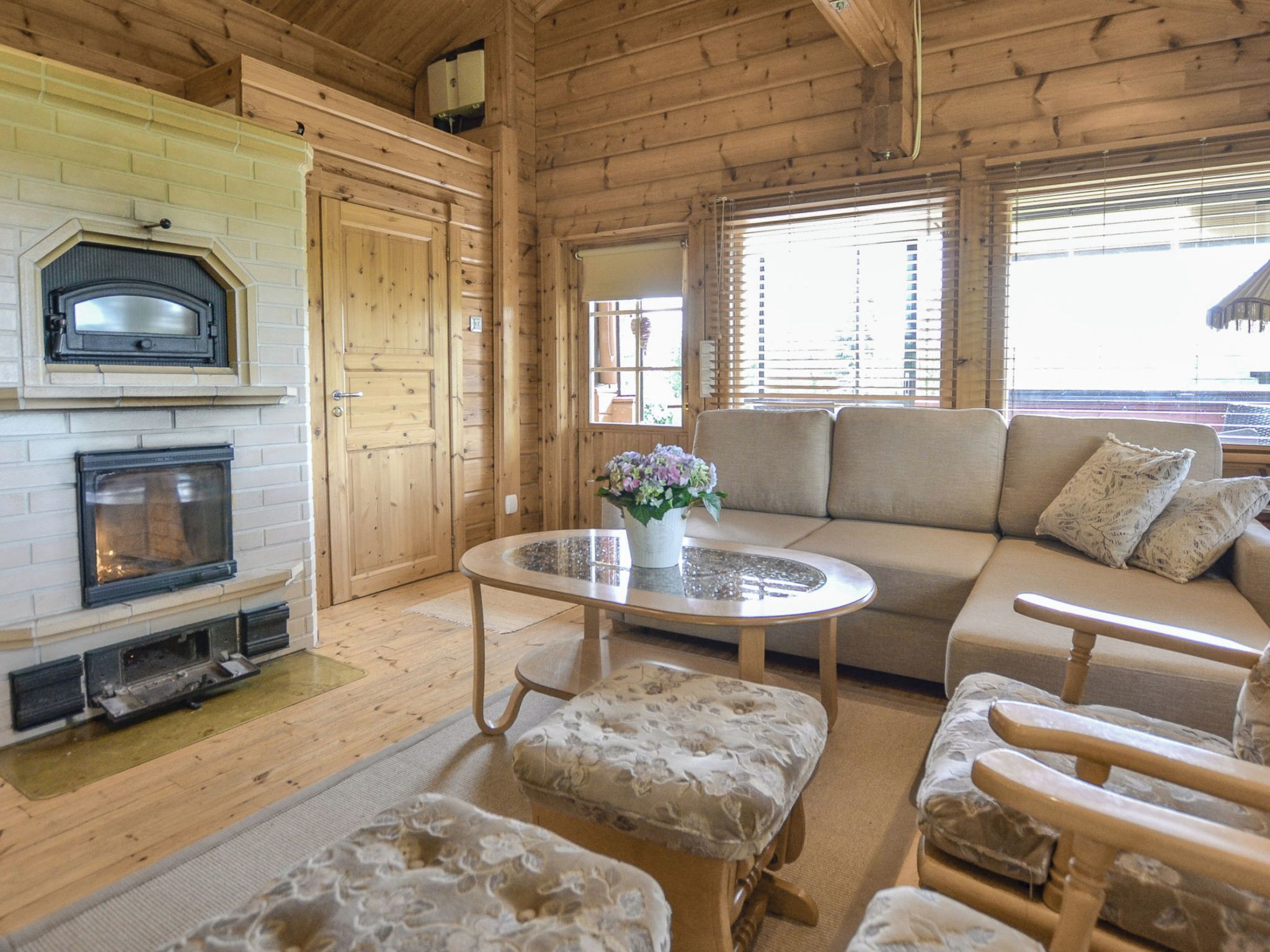 Un intérieur chaleureux de chalet en bois, avec une cheminée, un ensemble de canapés et une table basse ronde.