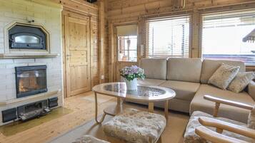 Un intérieur chaleureux de chalet en bois, avec une cheminée, un ensemble de canapés et une table basse ronde.