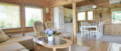 A wooden interior with a sofa, chairs, a dining table, and a kitchen area.