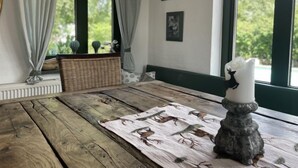 Ein rustikaler Holztisch mit einer gemusterten Tischmatte, einem dekorativen Kerzenhalter und gerahmten Bildern an der Wand.