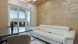 Un salon moderne avec un canapé blanc, une table en verre et une vue sur l’extérieur.