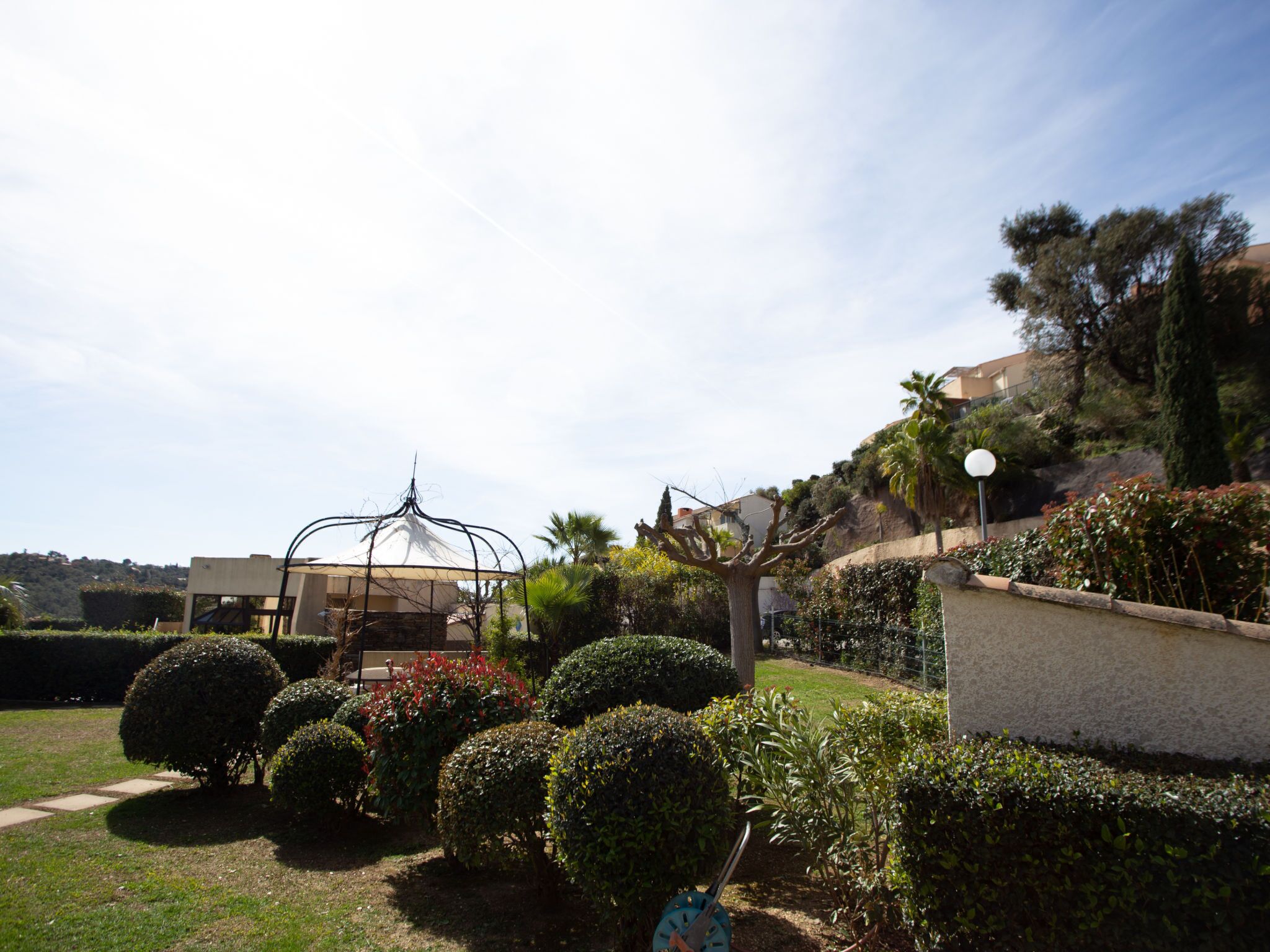 Un jardín con un porche, arbustos bien cuidados y un sendero.