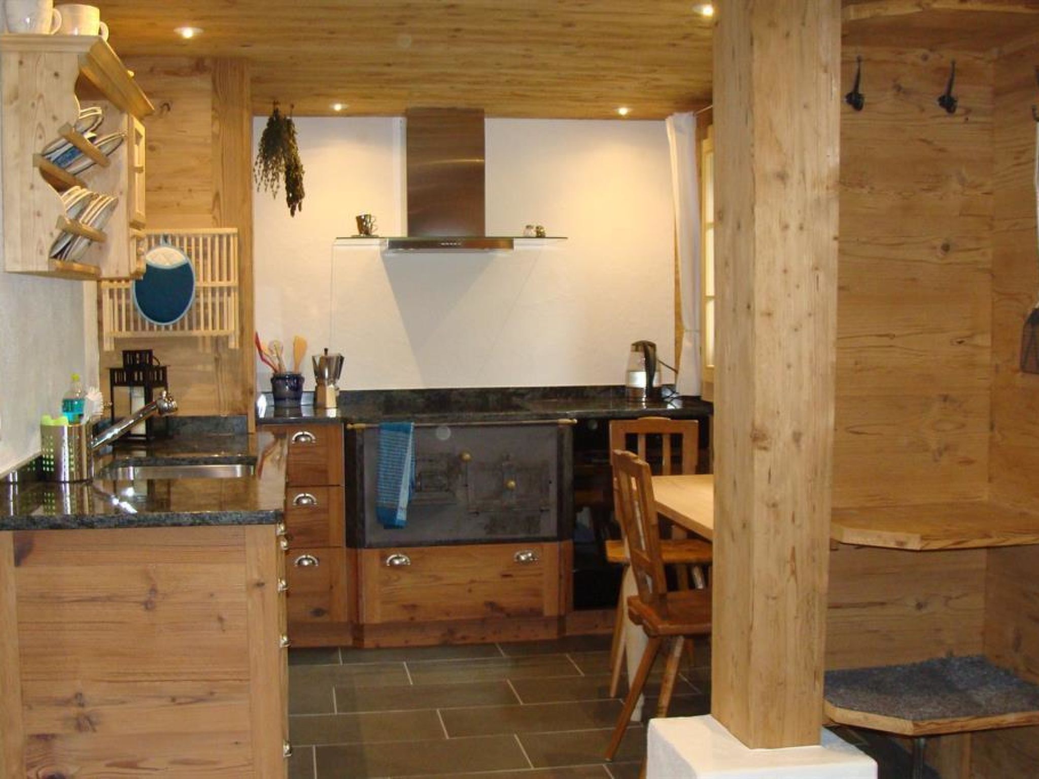 Cocina de estilo cabaña de madera con una isla central, armarios empotrados y una planta colgante.
