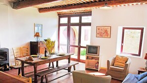 Ein gemütliches Wohnzimmer mit Holztisch, Stühlen, einer Couch und einem Fernseher.