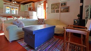 Un saló acollidor amb un sofà, un otomà blau, una cadira de fusta i una prestatgeria.