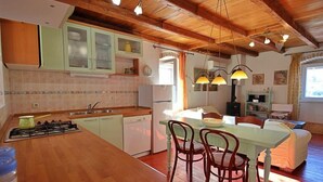 Une cuisine chaleureuse avec des meubles en bois, un coin repas avec des chaises et un îlot central.