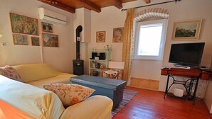 Un salon confortable avec un canapé, une petite table, un téléviseur et une cheminée.
