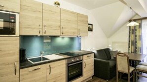 Une cuisine moderne avec des meubles en bois, un four encastré et un plan de travail noir.