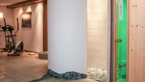 Un hall d’hôtel avec une grande colonne blanche, du matériel de musculation et une porte verte.