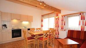 Una cucina compatta con mobili in legno, un tavolo da pranzo con sedie e un divano.