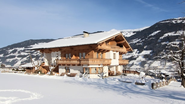 Una baita di legno con un balcone, immersa in montagne innevate.