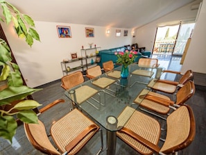 A modern meeting room with a glass table, wicker chairs, and a vase of flowers.