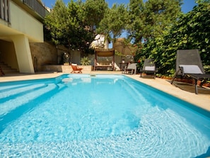 A clear blue swimming pool with lounge chairs and a covered seating area.