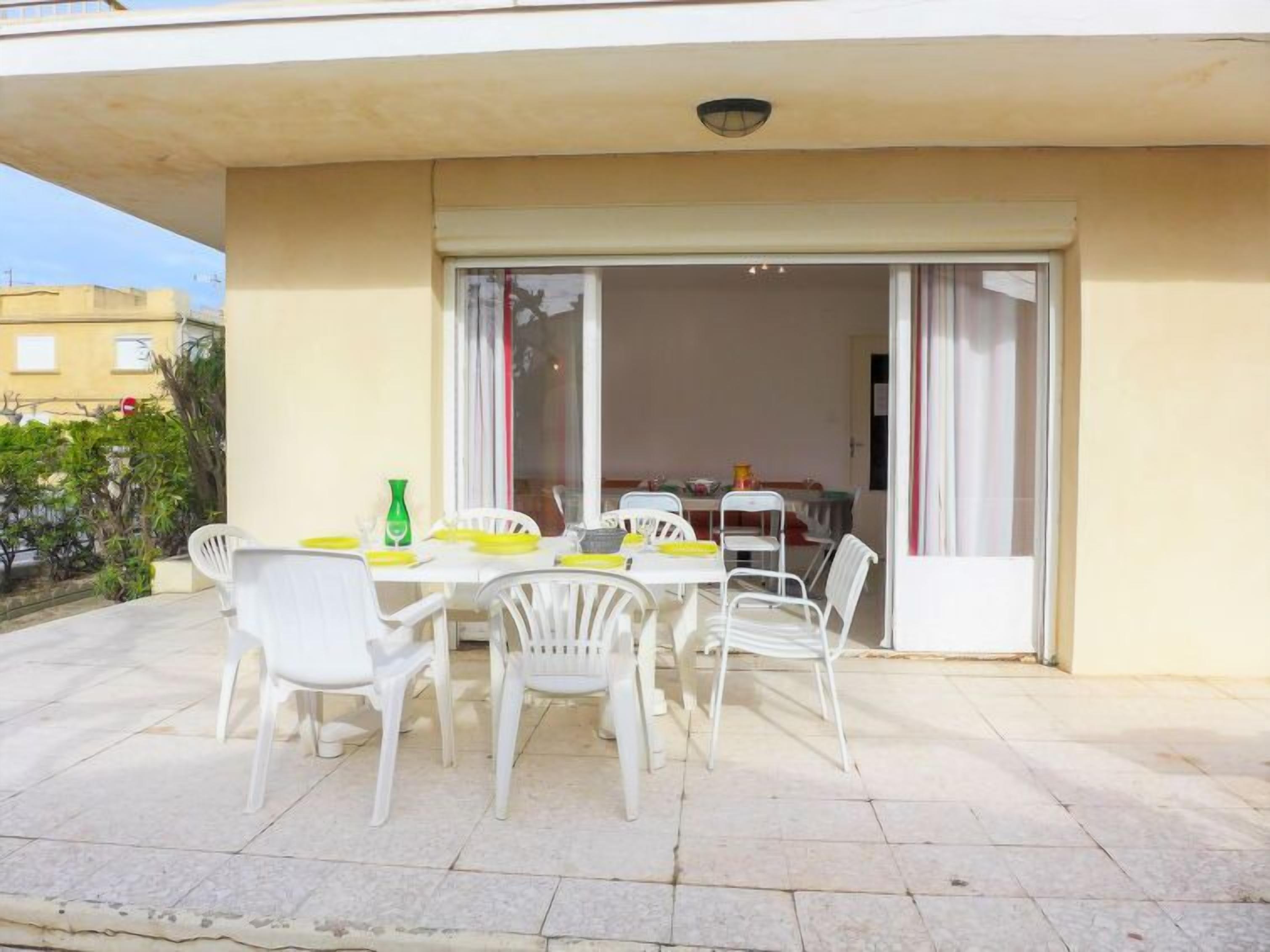 A patio with a table and chairs, a sliding glass door leading to an interior space, and a view of the surrounding area.