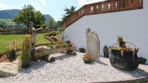 A garden with a white wall, wooden fence, and potted plants. - Gasteighof by Interhome (Fügen)