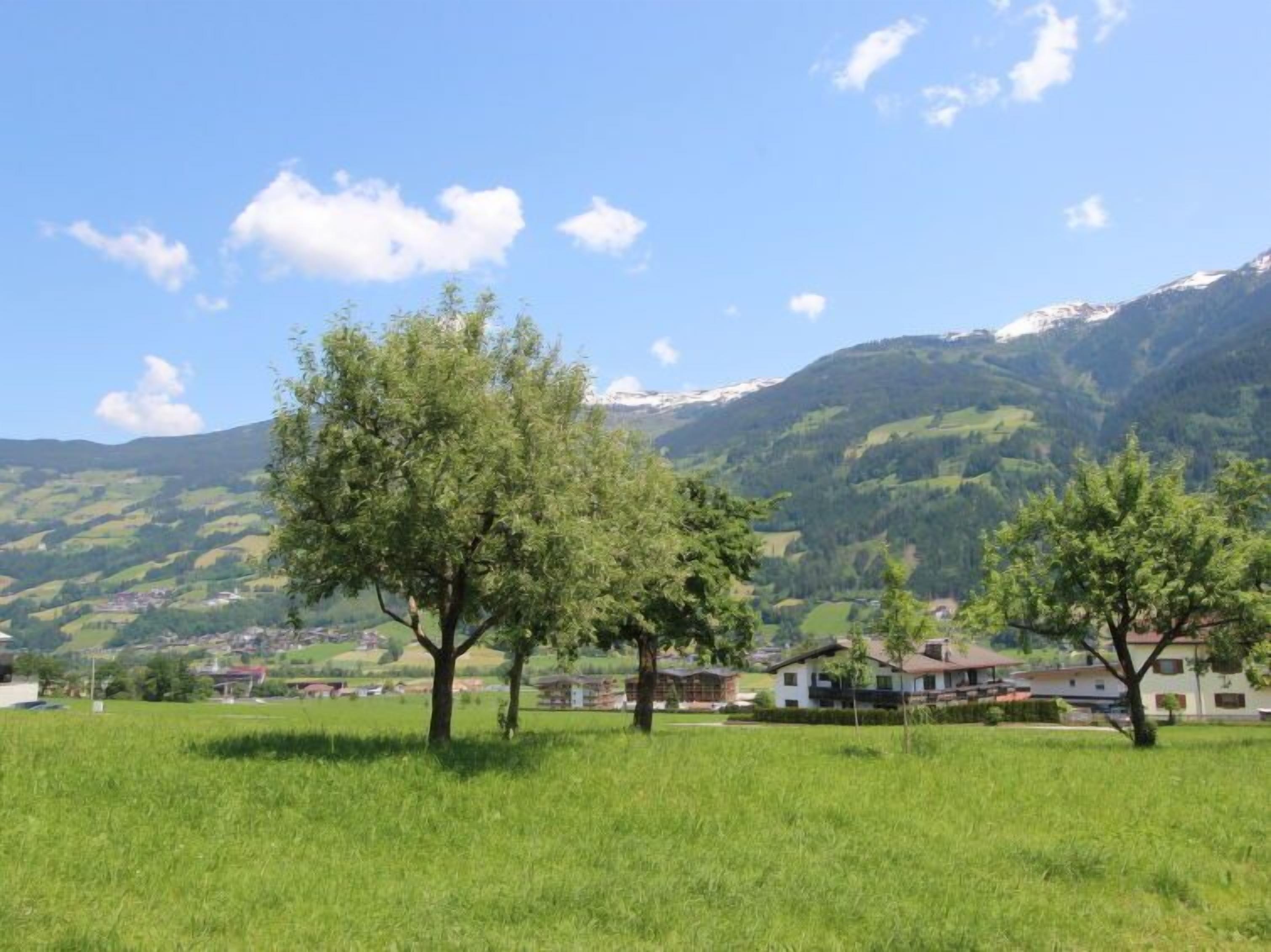 A rural landscape with a clear sky, green fields, and a few scattered houses.