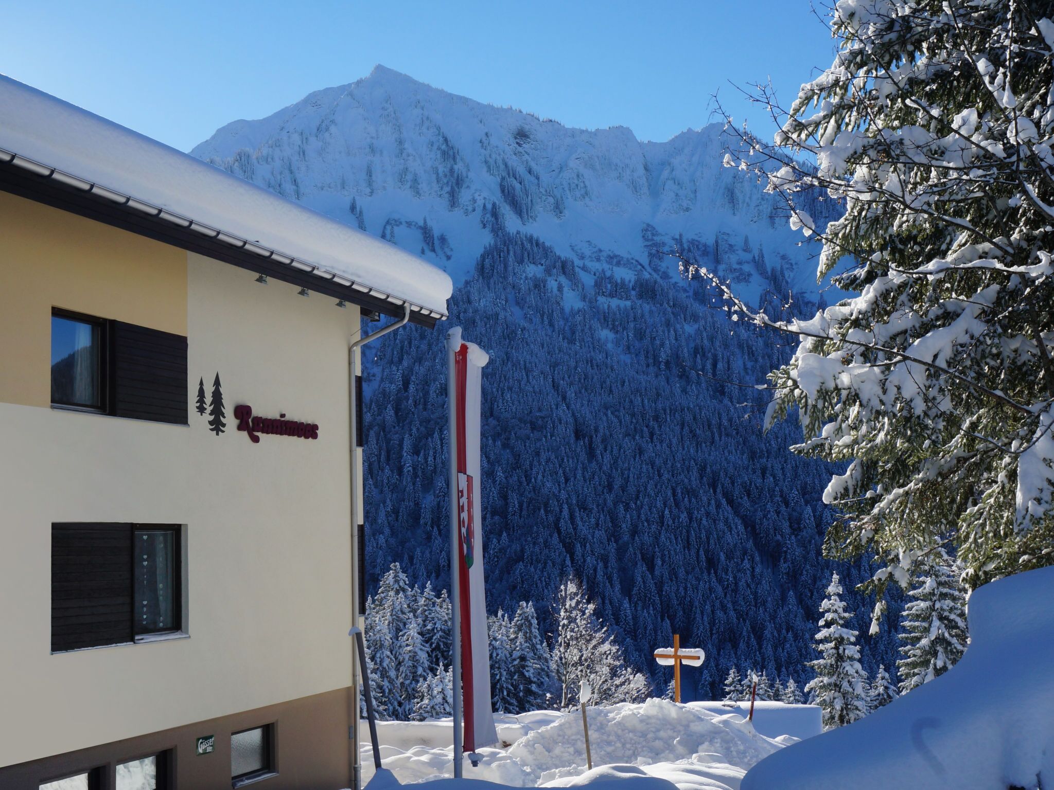 A building with a sign reading "Ruinweg" and a mountain backdrop.