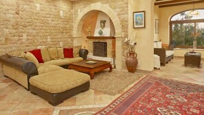 Una sala de estar con pared de piedra, chimenea, sofá, mesa de centro y vistas amplias por un gran ventanal.
