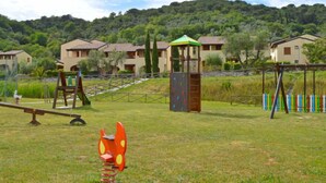 Un parque infantil con un sube y baja, una estructura para escalar y columpios.