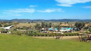 Un resort con asientos al aire libre, piscina y vistas a colinas distantes.