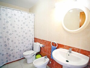 Ein Badezimmer mit Toilette, Bidet, Waschbecken, Spiegel und Duschvorhang.