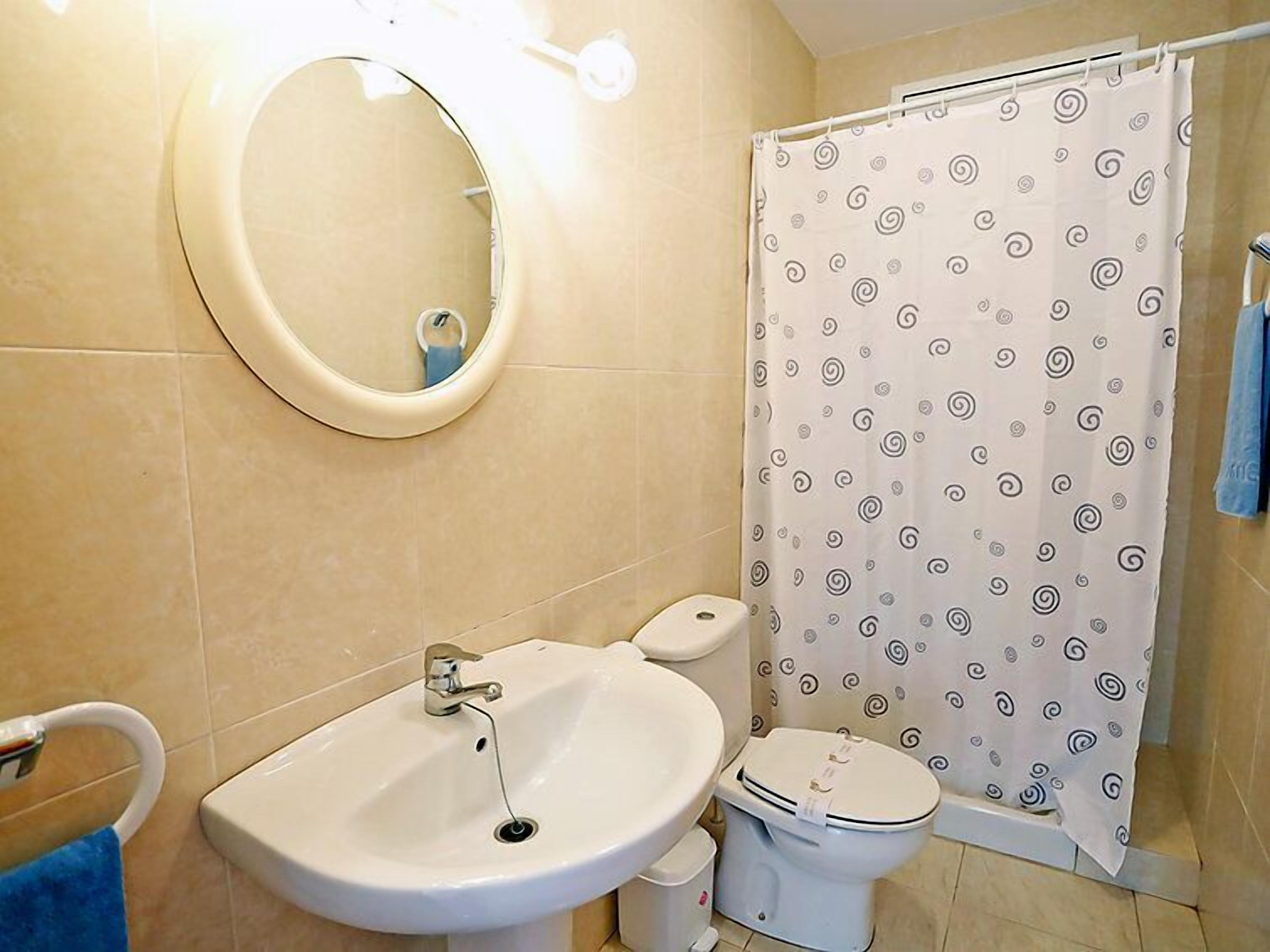 Ein Badezimmer mit Waschbecken, Toilette und einer Duschkabine mit Wirbelmuster.