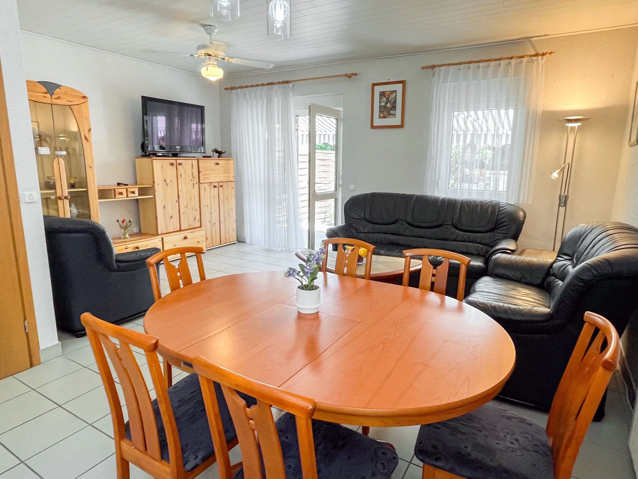 A living room with a wooden dining table, chairs, a sofa, and a TV.