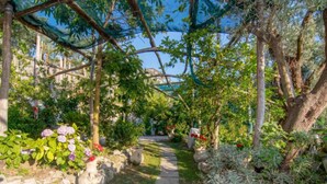 Un sendero en un jardín con muros de piedra y plantas en macetas.
