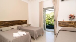 Habitación de hotel con dos camas, un candelabro, un equipo de aire acondicionado y vista a zonas verdes por la ventana.