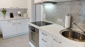 Une cuisine moderne avec des armoires blanches, un évier en acier inoxydable et un four encastré.