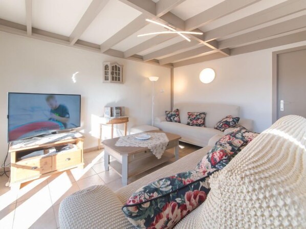 A living room with a TV, sofa, and wooden furniture.