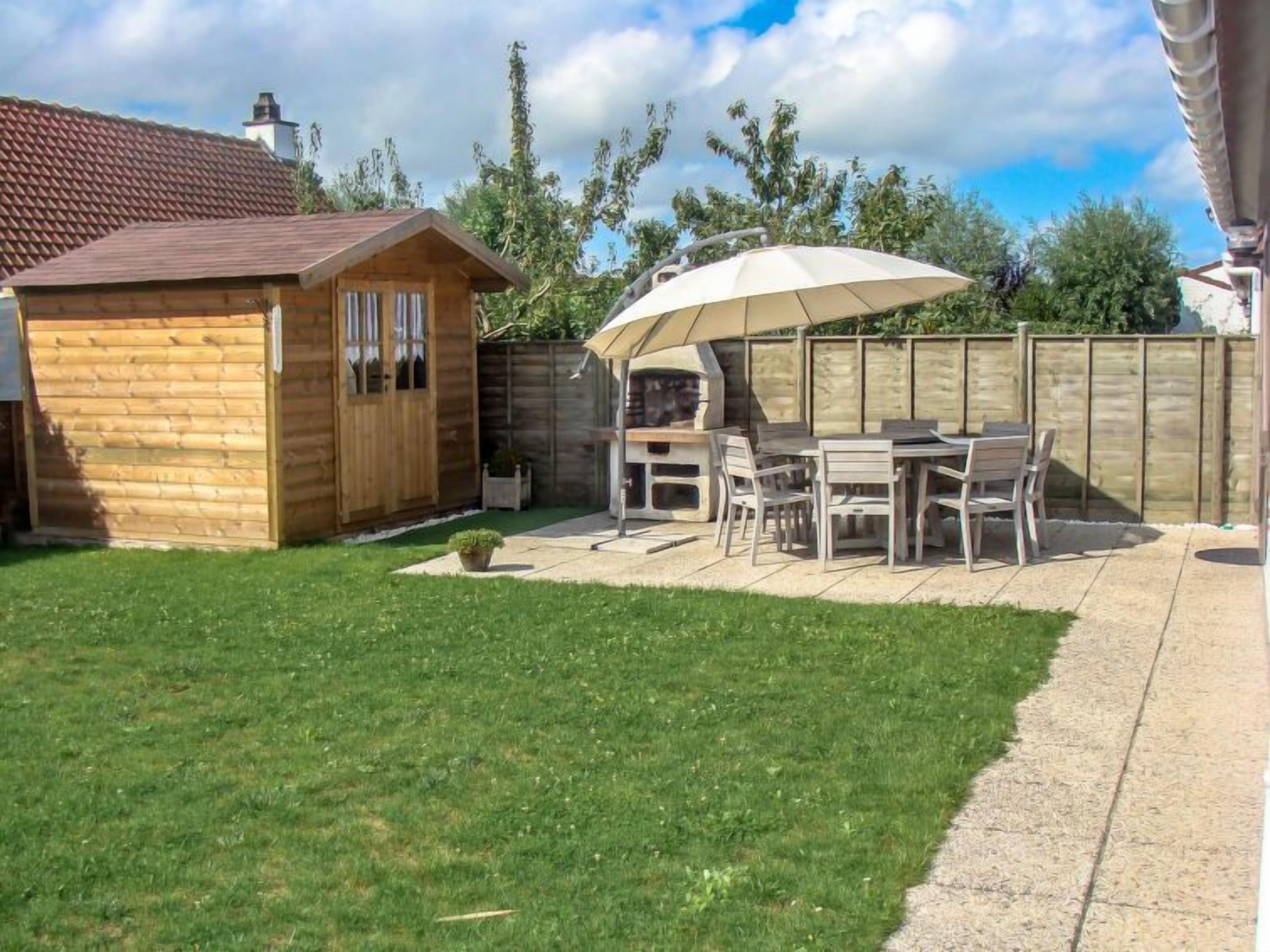 A wooden cabin with a patio area featuring a grill and outdoor seating.