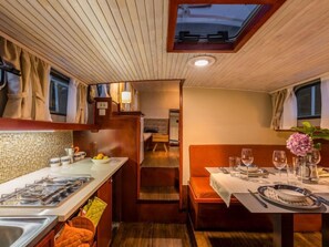Una cocina compacta con estufa, lavamanos y comedor con una mesa lista para dos.