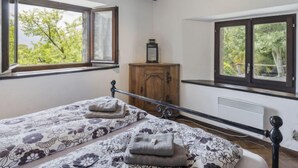 Une chambre avec deux lits, des poutres en bois, une fenêtre et un radiateur.