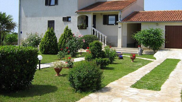 A two-story house with a tiled roof, a front porch, and a well-maintained garden with various plants and flowers. - Cvjetko by Interhome (Pula/Rakalj)