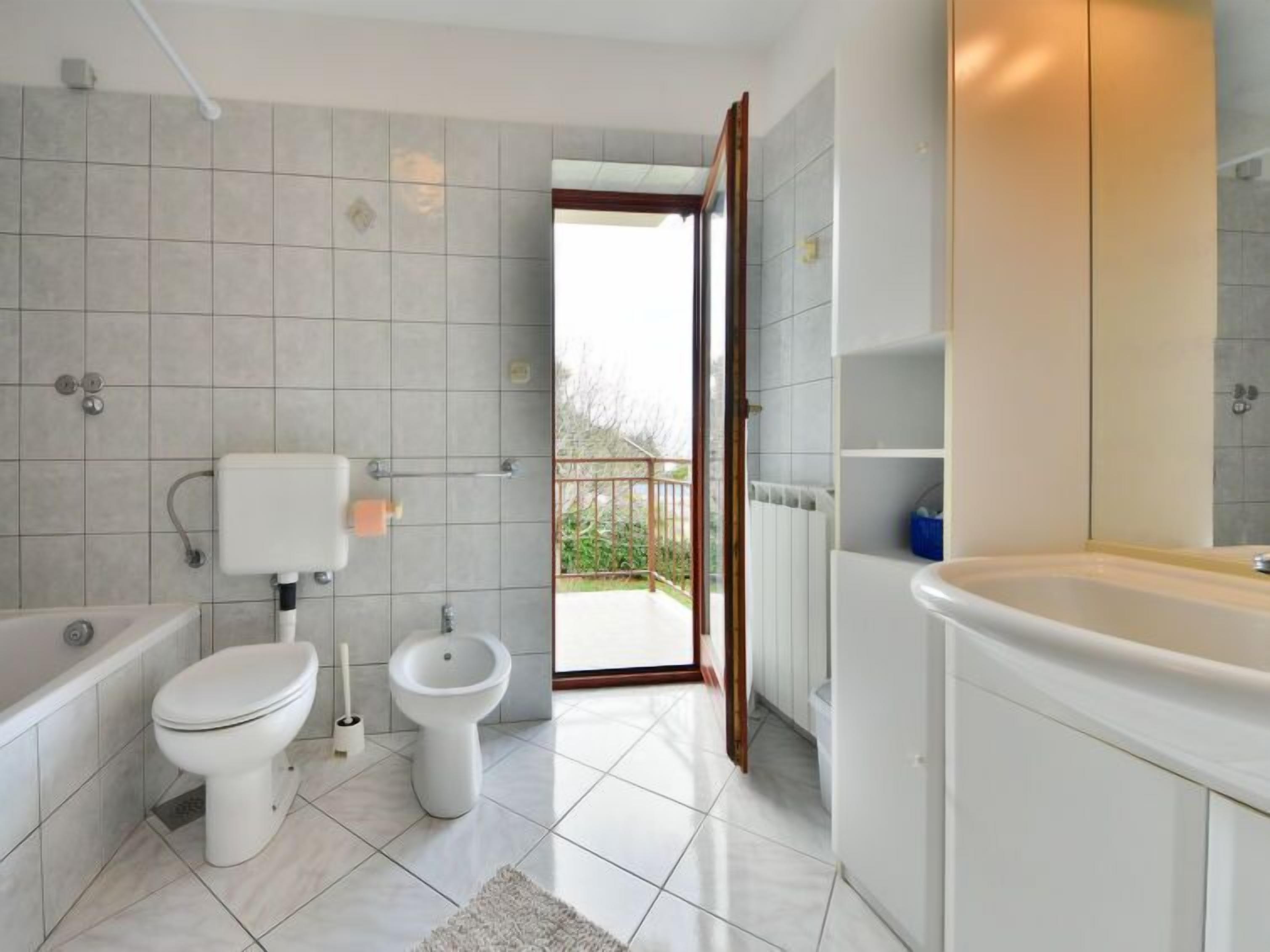 Een moderne badkamer met een bad, toilet, bidet en een groot wastafel.