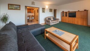 A living room with a sofa, a coffee table, a TV, and a cabinet.