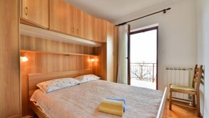A bedroom with a wooden bed, a nightstand, a chair, and a window with a view.