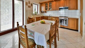 A kitchen with wooden cabinets, a dining table with chairs, and a refrigerator.