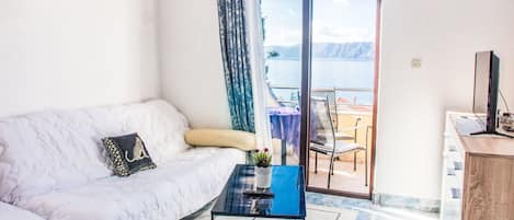 A modern room with a white sofa, a small coffee table, and a view of the sea through a glass door.