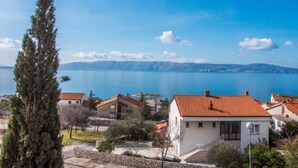 Un quartier résidentiel situé sur la côte, avec des maisons, un ciel bleu dégagé et une vue sur la mer.