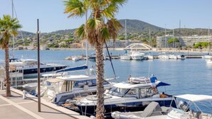 Un port de plaisance avec des bateaux amarrés, des palmiers et un pont en arrière-plan.