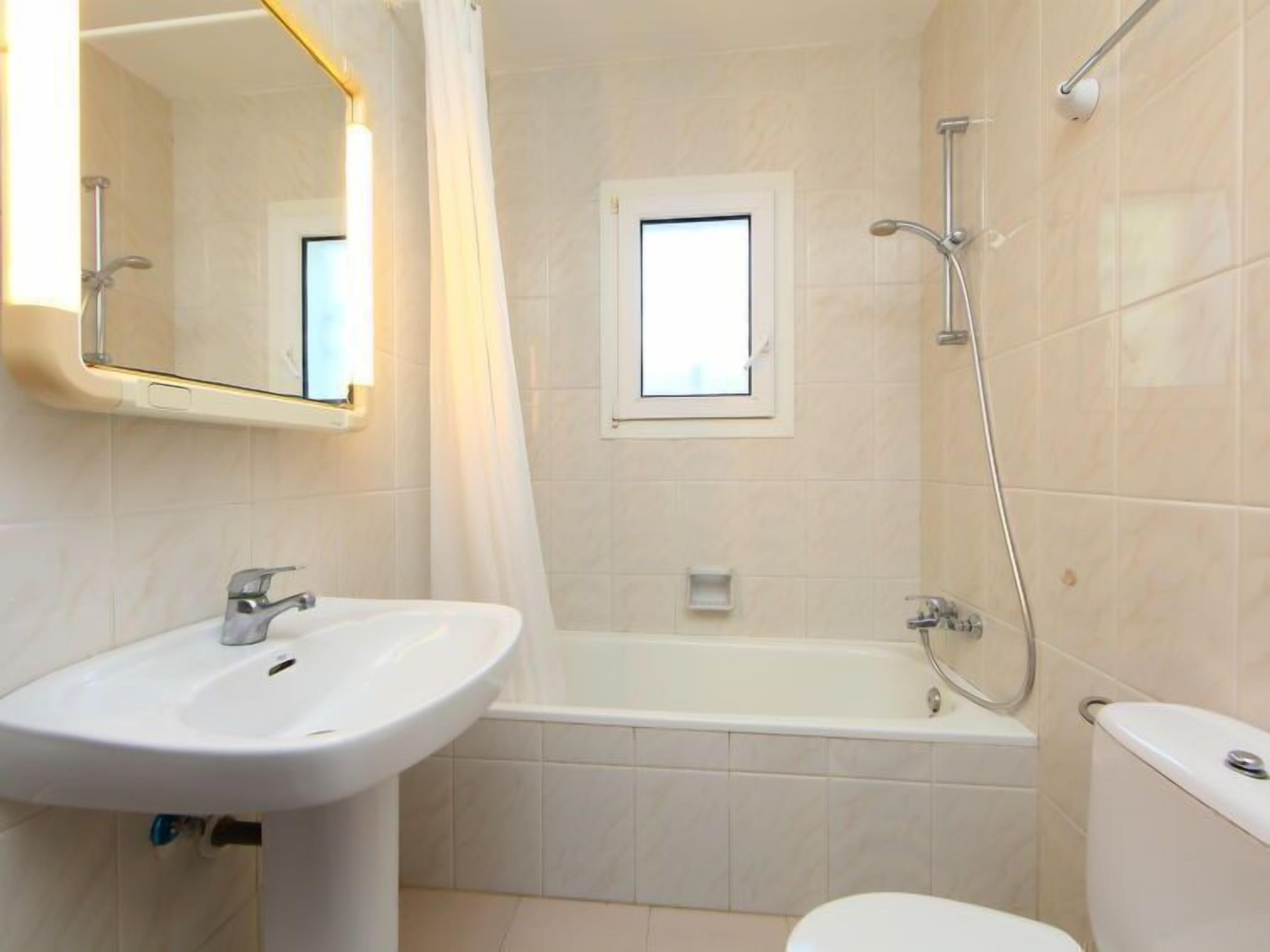 A bathroom with a sink, toilet, bathtub, and a window.