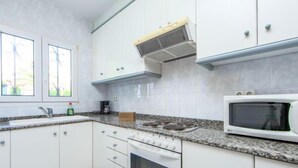Eine moderne Küche mit weißen Schränken, einem eingebauten Backofen, einer Mikrowelle und einer Kaffeemaschine.